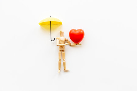 Wooden figurine of a man with umbrella and heart. Medical insurance concept.の写真素材