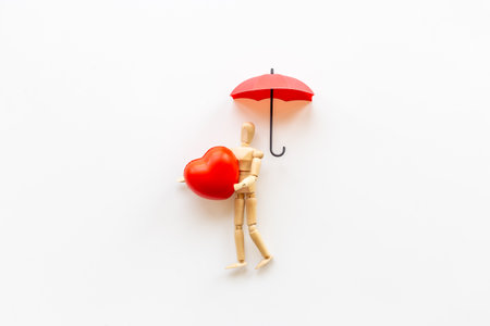Wooden figurine of a man with umbrella and heart. Medical insurance concept.の写真素材