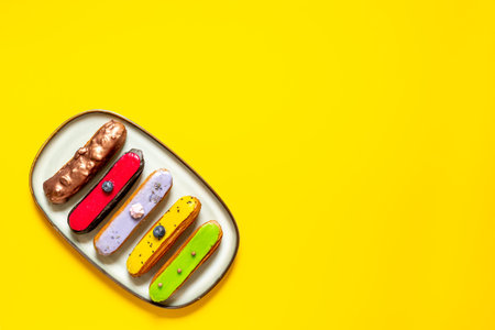 Set of various glazed eclairs with chocolate and berry, top view.