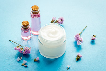 Glass vial of cosmetic face skin care cream with flowers.の写真素材
