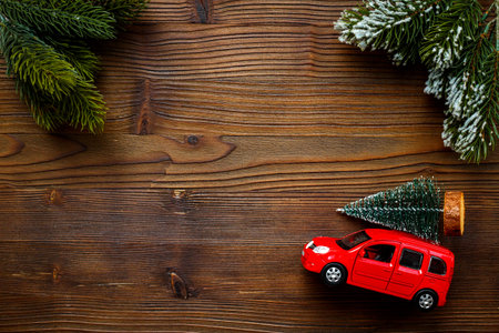 Red toy car carrying Christmas tree. Festive New Year decoration and Christmas backgroundの写真素材