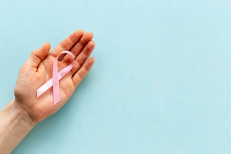 Pink ribbon symbol of breast cancer with hands. Medical support and prevention.の写真素材