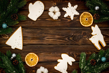 Frame of white Christmas cookies with fir tree branches. New Year background