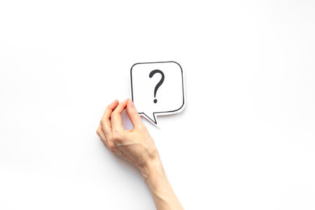 Hand holding question mark on paper speech bubble, top view.の写真素材