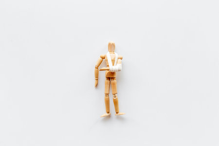 Wooden dummy man with broken arm - arm in bandage. Medical insurance and healthcare concept.の写真素材