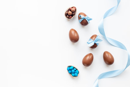 Easter festive background. Chocolate Easter eggs in blue ribbon with sweets.の写真素材