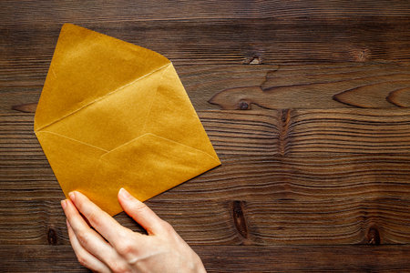 Hand holds blank paper envelope for letters. Space for text, top view.