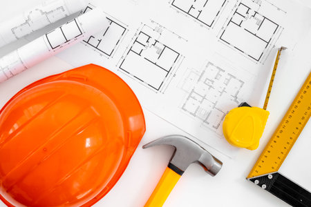 Construction helmet on drawing blueprints for house designing and architect plan