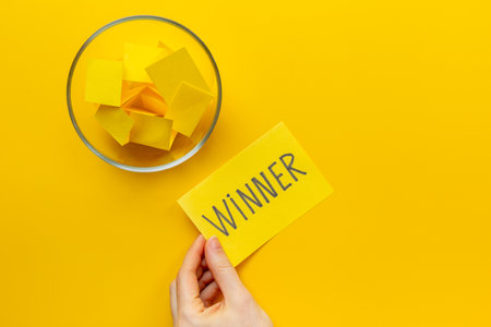 Female hand holding lottery ticket with winner word near glass bowl full of paper sheets. Winner concept.の写真素材