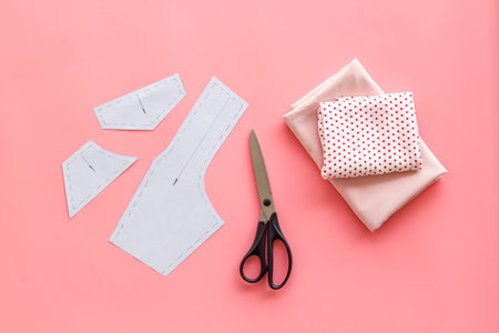 Tailors workplace with sewing patterns and cotton dress fabric, top view.