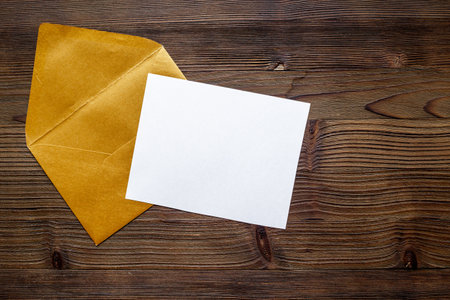 Blank white paper on the golden envelope. Mockup of letter or greeting card. Top view.の写真素材