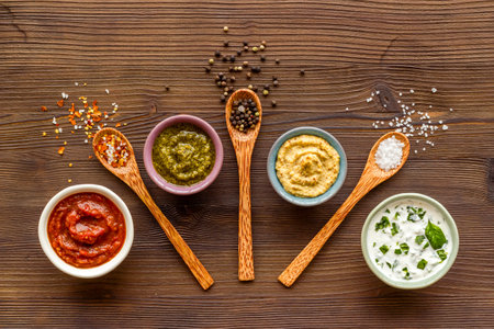Many different sauces in bowls and spices in spoons, top view. Food or cooking background.