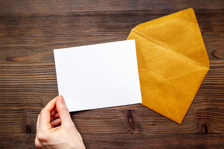 Hand holds blank paper against envelope for letters. Space for text, top view.の写真素材