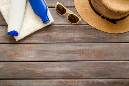 Summer holiday beach background. Male straw hat with sunscreen and sunglasses, top view.の写真素材