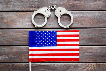 Metal handcuffs for criminals with USA flag. Local criminal law and justice concept.の写真素材