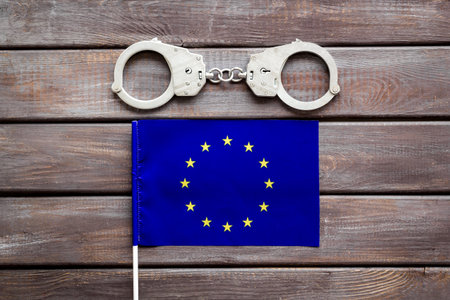 Metal handcuffs for criminals with EU flag. Europe criminal law and justice concept.の写真素材
