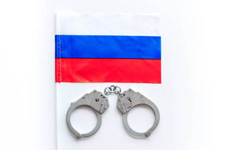 Metal handcuffs for criminals with Russian flag. Local criminal law and justice concept.の写真素材