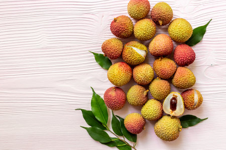 Juicy lychee fruit with cut in half and green leaves, top view. Fresh ripe tropical fruit.の写真素材