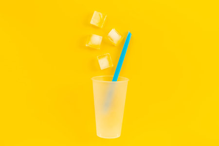 Disposable cup with ice and straw for cocktails. Cold drink concept.