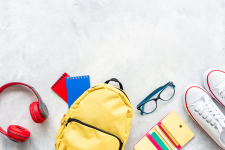 Flatlay of yellow backpack with wallet and bank cards and headphones, top view