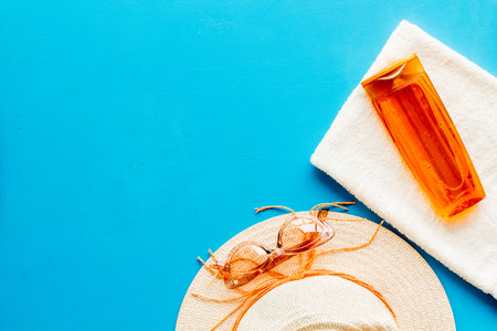 Summer holiday beach background. Female straw hat with sunscreen and sunglasses, top view.の写真素材