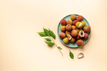 Lychee with green leaf on the plate, top view. Tropical fruits background.の写真素材