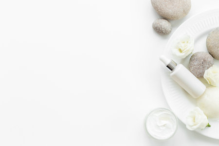 White roses and stones with skin care cosmetics products. Mock up, top view.の写真素材