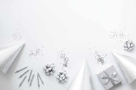 Party background in silver monochrome color. Gift box with cake candles and party hats, top view.の写真素材