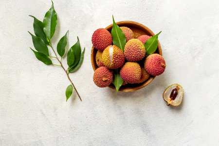 Lychee fruit with green leaf in wooden bowl, top view. Fresh ripe tropical fruit.の写真素材