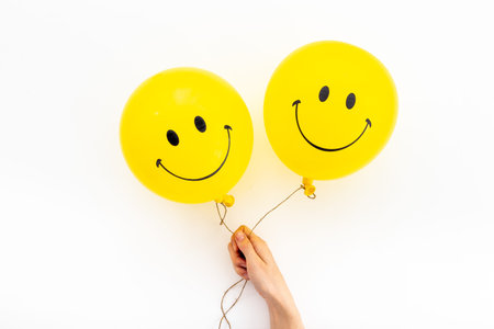 Hands holding smiling yellow balloon. Optimistic mind concept.の写真素材