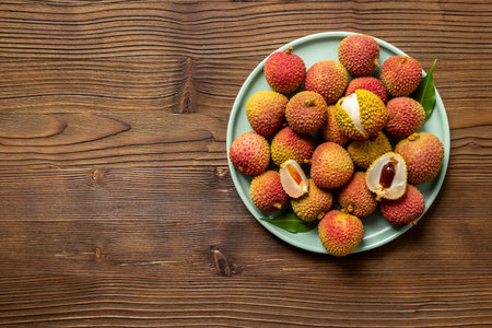 Juicy lychee fruit with cut in half and green leaves, top view. Fresh ripe tropical fruit.の写真素材
