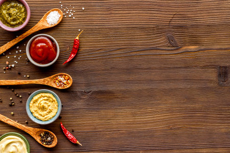 Many different sauces in bowls and spices in spoons, top view. Food or cooking background.