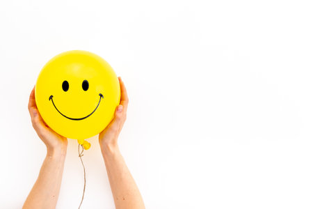 Hands holding smiling yellow balloon. Optimistic mind concept.の写真素材