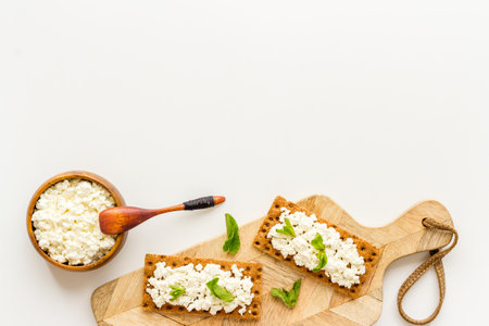 Crispy toasts with farm cottage cheese on wooden board, top view.の写真素材
