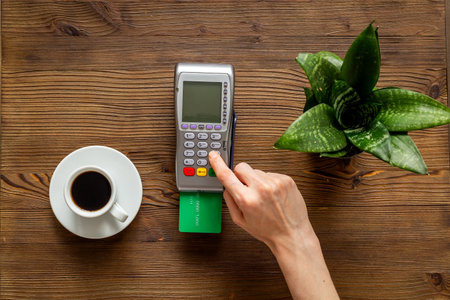 Paying a bill at a cafe - female hands with wireless bank payment terminal and credit cardの写真素材