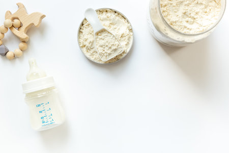 Milk for baby in a bottle with powdered milk in a spoon on white background, top view.の写真素材