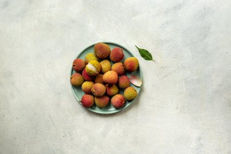 Juicy fresh lychee fruit with cut in half and green leaves on the plate, top view.の写真素材