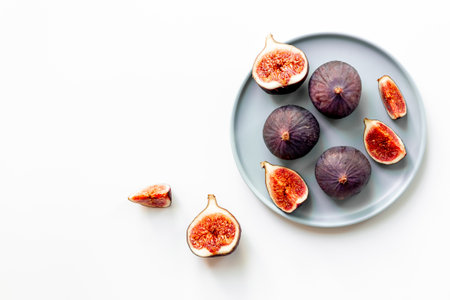 Plate with fresh ripe figs whole and slices on white background. Top view.の写真素材
