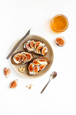 Figs and cheese toasts on the plate with jar of honey, top view.