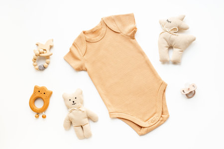 Flat lay with beige baby bodysuit and eco friendly toys on white background, top view.の写真素材