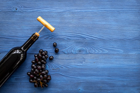 Red wine in the bottle with bunch of grapes and corkscrew, top view