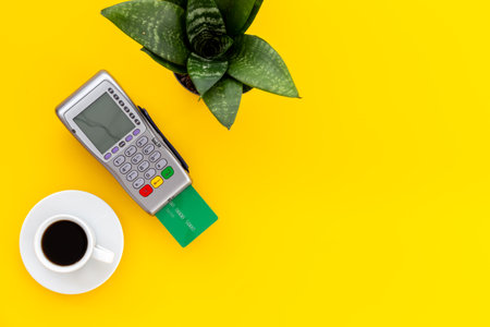 Pos bank terminal for payment by credit card with cup of coffee in cafe, top view.の写真素材