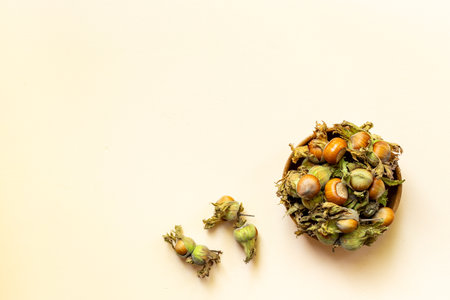 Hazelnuts with leafy shells in wooden bowl, top view. harvest time.の写真素材