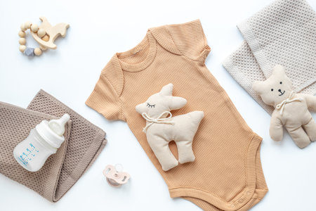 Cotton baby bodysuit and eco friendly toys on white background, top view.の写真素材