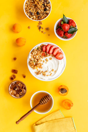 Bowl with yogurt and oatmeal served with honey and strawberry, top view.の写真素材