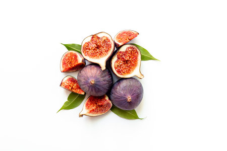 Whole and cut fresh figs with green leaves on white background. Top view.の写真素材