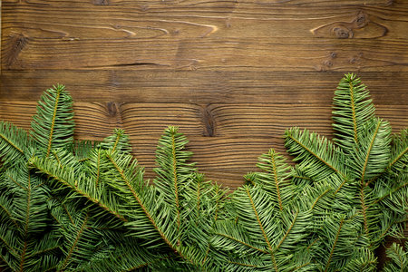 Green pine branches isolated on a wooden background, top view. Festive winter holiday themes.の写真素材