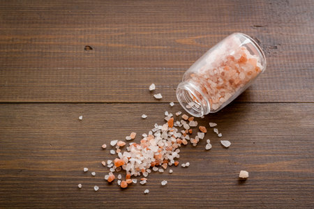 Coarse pink salt in salt shaker and spilled salt.の写真素材
