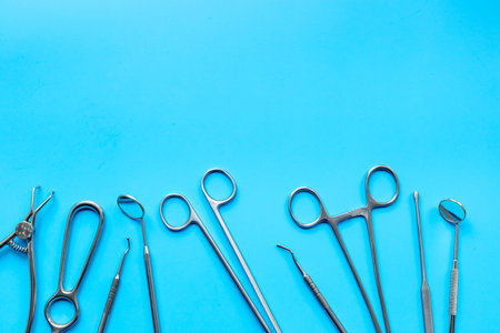 Surgical scissors and forceps. Medical metal hand tools and equipment on blue, top view.