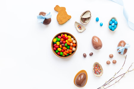 Top view of lots of chocolate Easter eggs with blue ribbon on a white background.